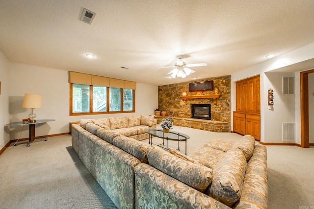 living room with a textured ceiling, ceiling fan, light carpet, and a fireplace