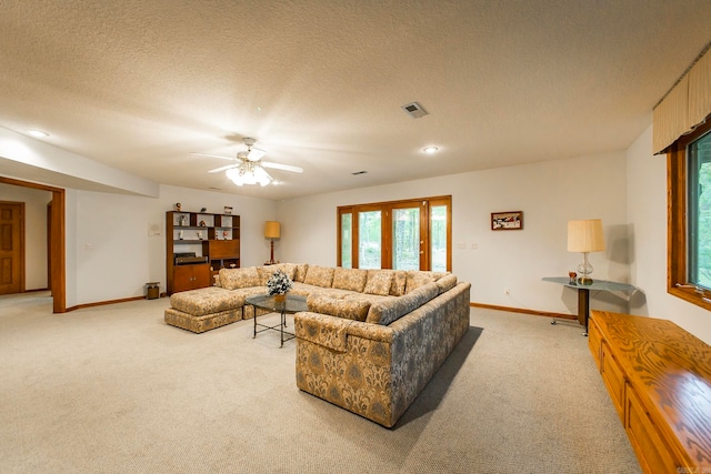 living room featuring a textured ceiling, light colored carpet, and ceiling fan