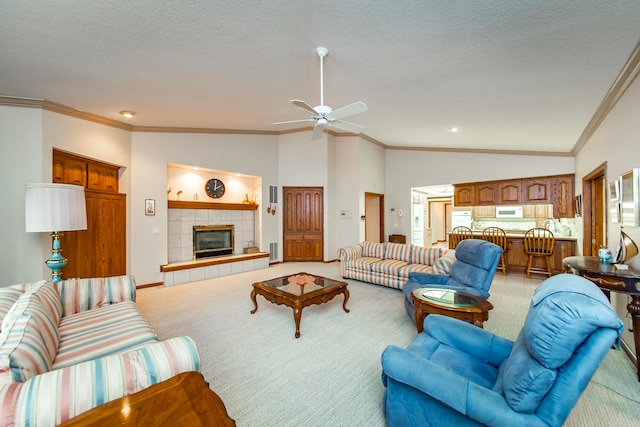 living room featuring ceiling fan, a tile fireplace, a textured ceiling, and light colored carpet