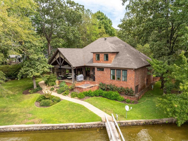 view of front of property with a boat dock, a patio, a water view, and a front lawn