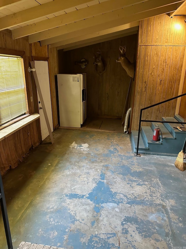 basement with wood walls and white refrigerator