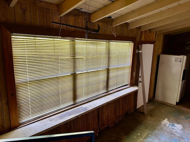 interior space featuring concrete floors, wood walls, white fridge, and beam ceiling