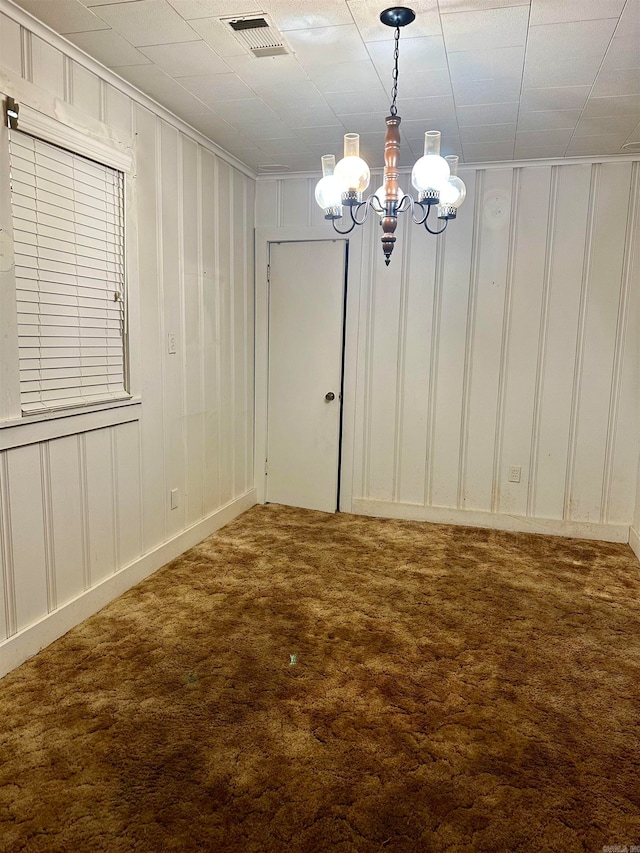 carpeted empty room featuring an inviting chandelier