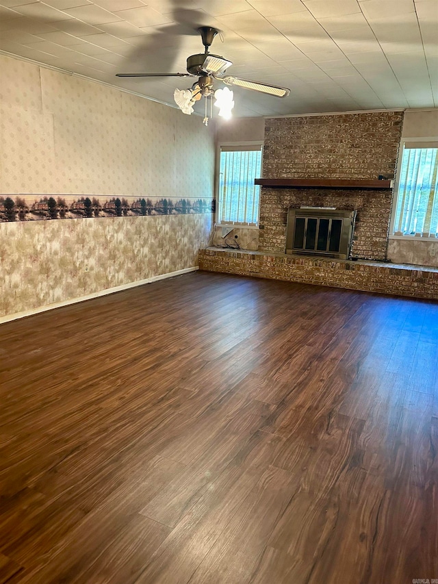 unfurnished living room with plenty of natural light, a brick fireplace, ceiling fan, and dark hardwood / wood-style floors