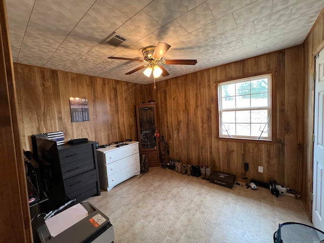 interior space featuring ceiling fan and wooden walls