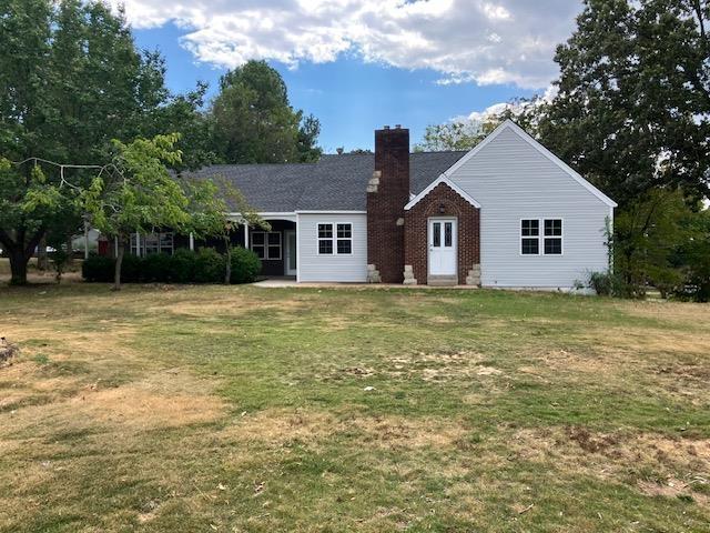 view of front facade with a front lawn, a chimney, and brick siding