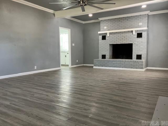 unfurnished living room with baseboards, dark wood finished floors, a ceiling fan, crown molding, and a fireplace