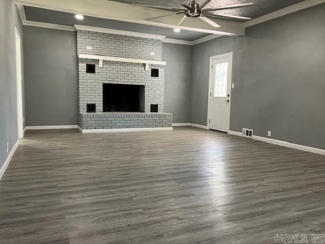 unfurnished living room featuring ornamental molding, a brick fireplace, dark wood-type flooring, and ceiling fan