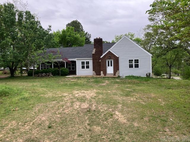 view of front of home featuring a front yard, brick siding, and a chimney