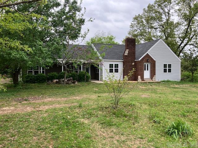 single story home featuring brick siding, a chimney, and a front lawn