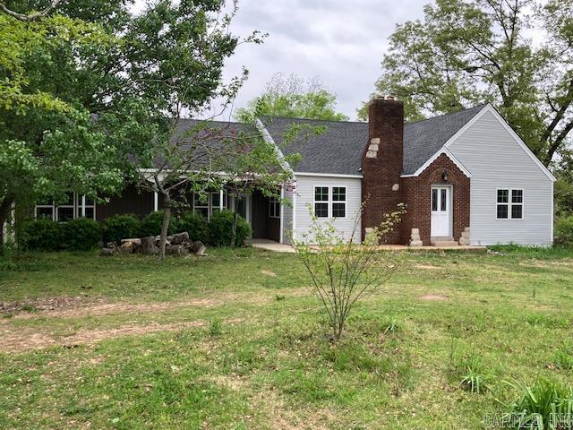 single story home featuring a chimney and a front lawn