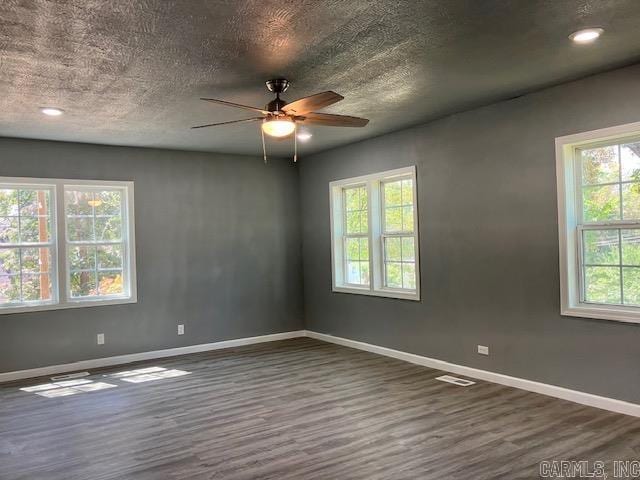 empty room featuring ceiling fan, baseboards, dark wood finished floors, and a textured ceiling