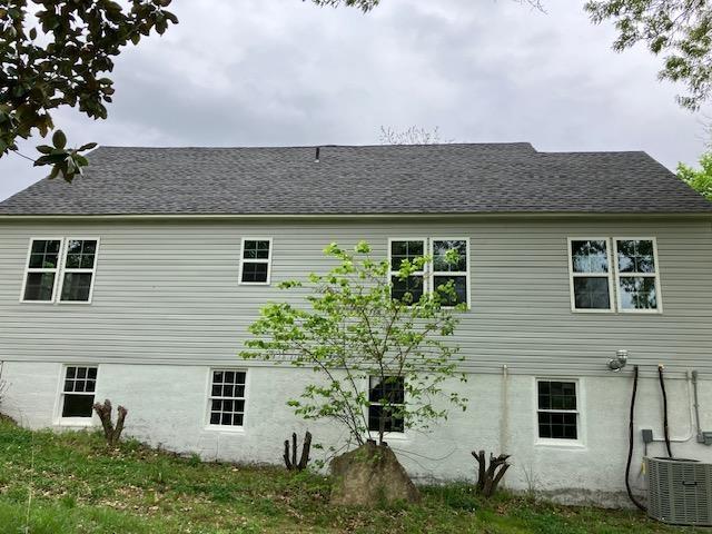 back of property featuring central AC and a shingled roof