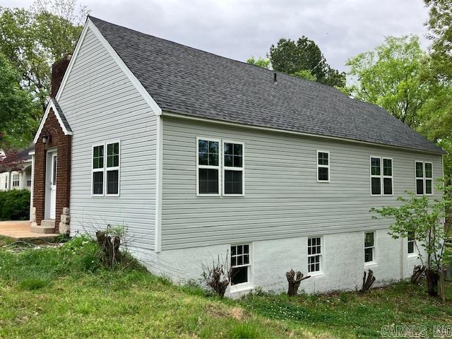 view of side of home with a yard and a shingled roof