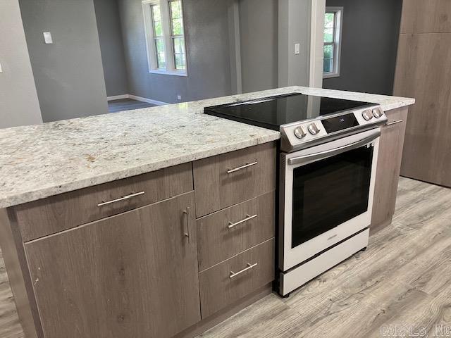 kitchen featuring modern cabinets, light stone countertops, light wood-style flooring, and stainless steel range with electric cooktop