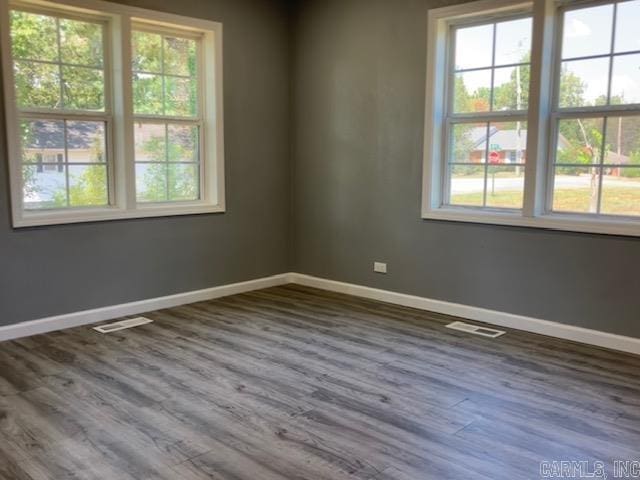 spare room with visible vents, baseboards, and dark wood-type flooring