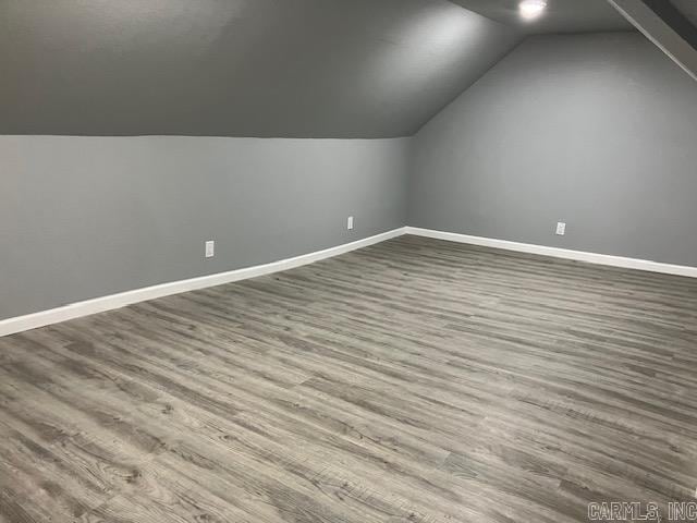 bonus room featuring lofted ceiling, dark wood finished floors, and baseboards