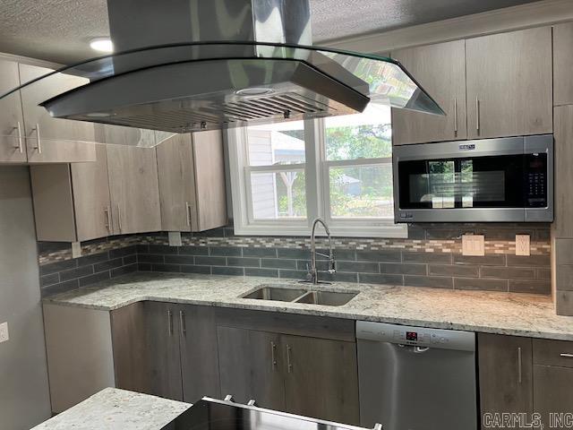 kitchen with a sink, appliances with stainless steel finishes, ventilation hood, backsplash, and light stone countertops