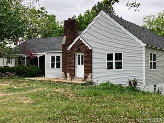 rear view of house featuring roof with shingles, a yard, and a chimney