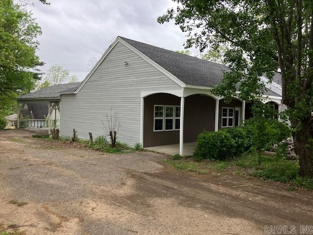 view of side of property with covered porch and a shingled roof