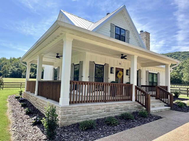 view of front of property featuring a standing seam roof, fence, board and batten siding, covered porch, and metal roof