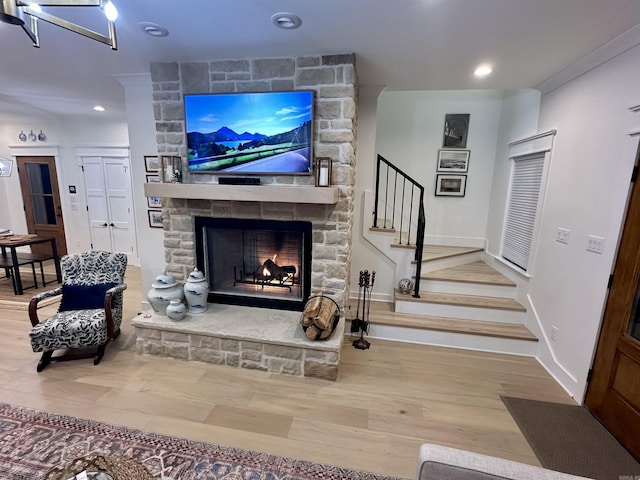 living area featuring wood finished floors, recessed lighting, stairway, a stone fireplace, and baseboards