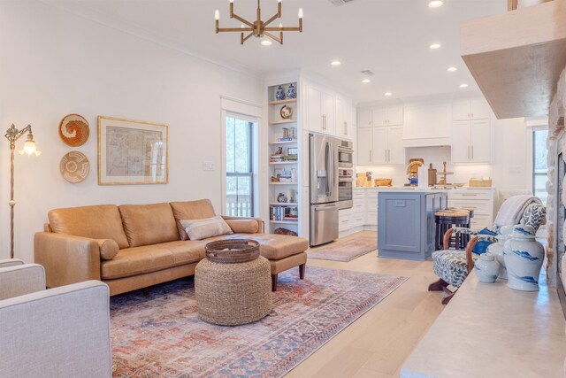 living room featuring a notable chandelier, crown molding, and light hardwood / wood-style flooring