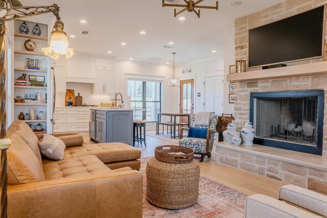 living room with a stone fireplace, recessed lighting, light wood-style floors, and visible vents