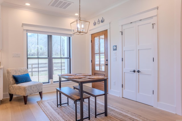 dining area with crown molding, a healthy amount of sunlight, a chandelier, and light hardwood / wood-style floors