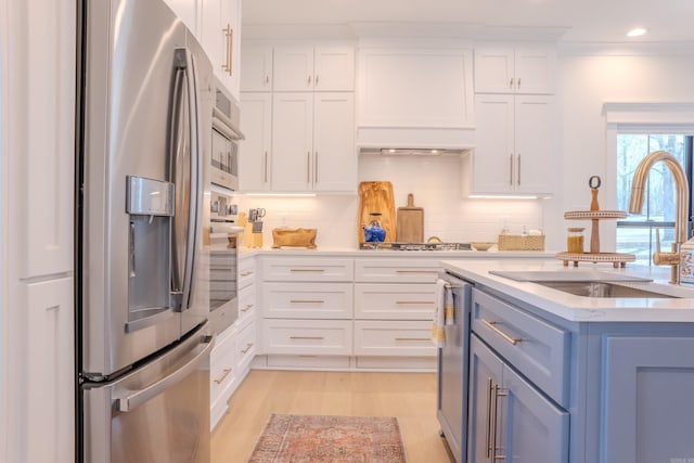 kitchen with backsplash, light countertops, appliances with stainless steel finishes, white cabinets, and a sink