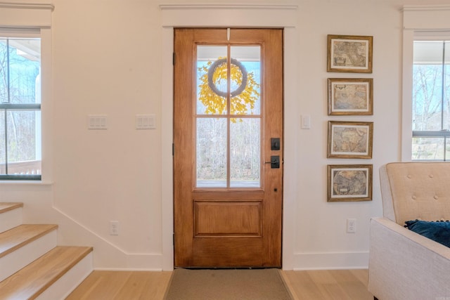 foyer entrance with a wealth of natural light, baseboards, wood finished floors, and stairs