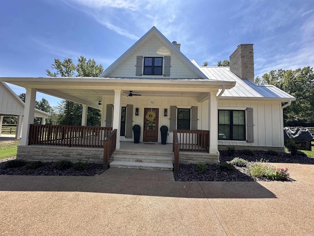 view of front of property featuring board and batten siding, covered porch, a chimney, metal roof, and a standing seam roof