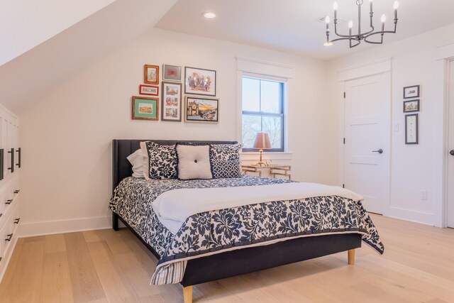 bedroom featuring lofted ceiling, light hardwood / wood-style flooring, and a chandelier