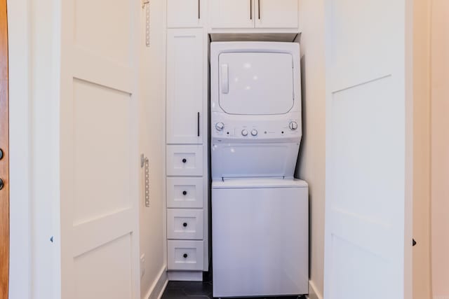 washroom featuring dark tile patterned flooring, cabinets, and stacked washer / drying machine