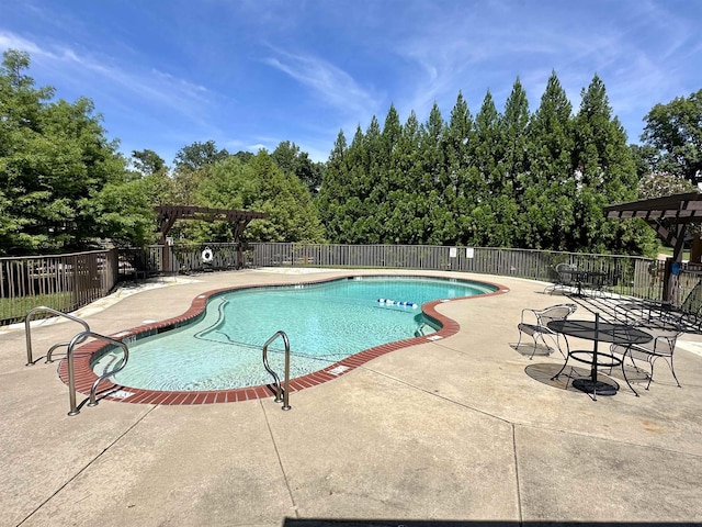 pool with a patio area and fence