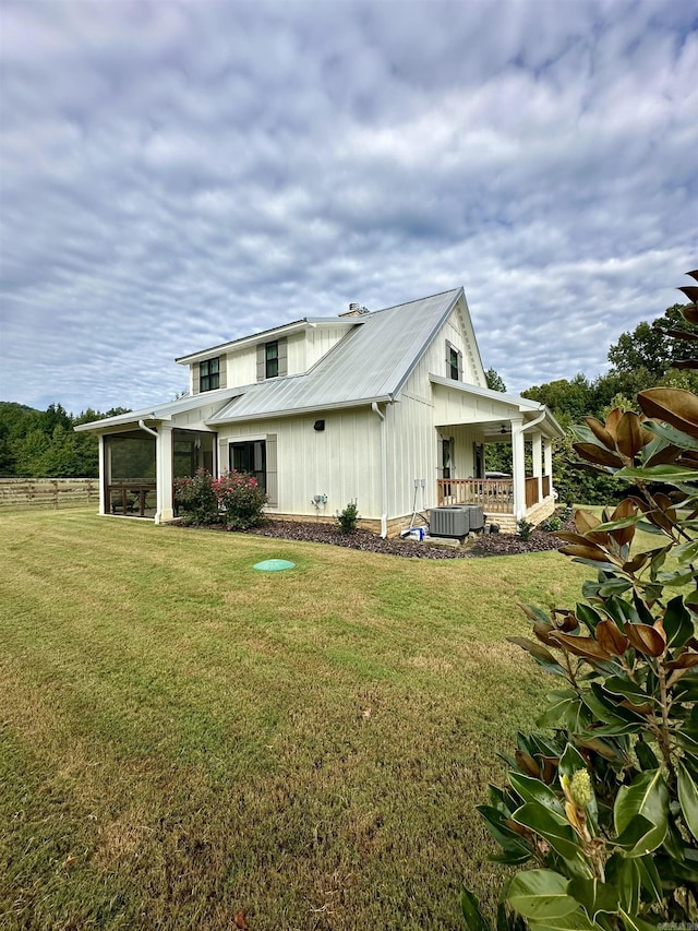 exterior space featuring metal roof, central AC, a front lawn, and a sunroom