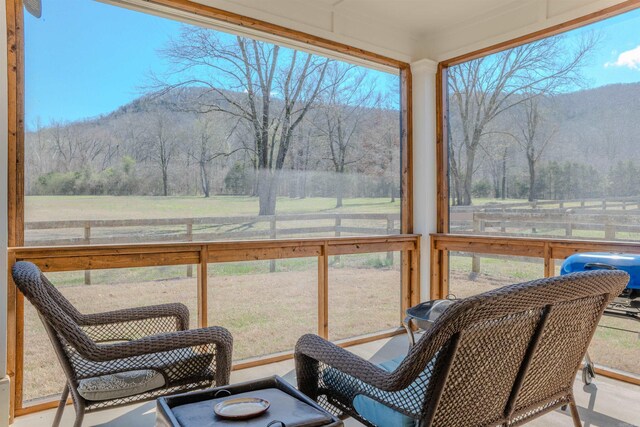 sunroom featuring a mountain view and a rural view