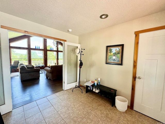 interior space with a textured ceiling, vaulted ceiling, and light hardwood / wood-style floors