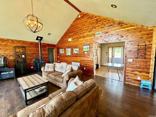 living room featuring high vaulted ceiling, a notable chandelier, a wood stove, wood-type flooring, and beam ceiling