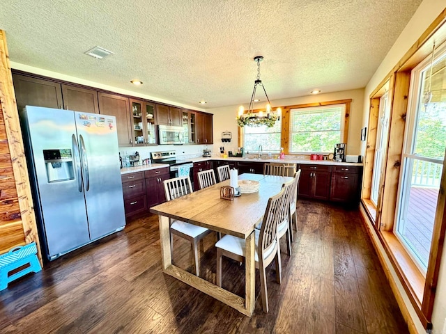 dining room featuring an inviting chandelier, dark hardwood / wood-style flooring, a textured ceiling, and a healthy amount of sunlight