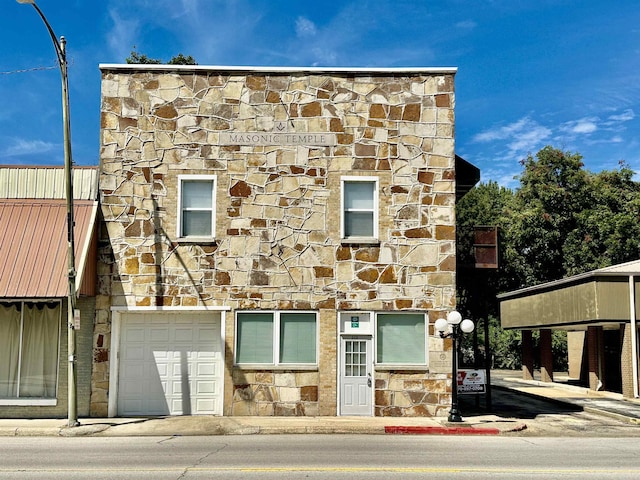 townhome / multi-family property with stone siding and an attached garage