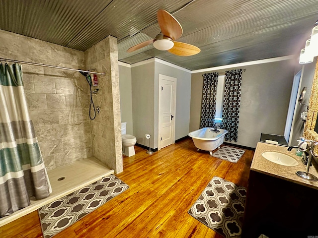 full bath with wood finished floors, a tile shower, crown molding, baseboards, and vanity