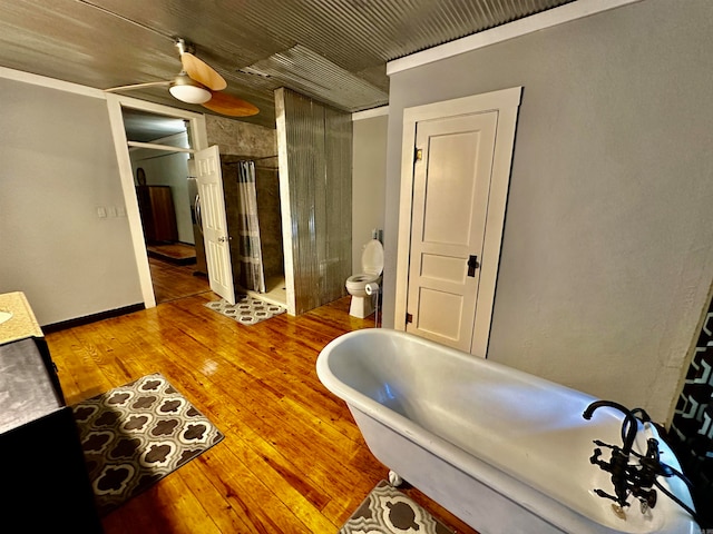 full bathroom with a shower stall, toilet, a freestanding tub, vanity, and wood-type flooring