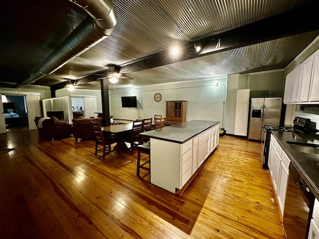 kitchen featuring dark countertops, white cabinetry, black appliances, and light wood-style floors