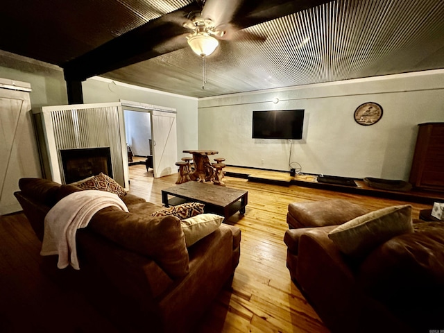 living room with a barn door, a fireplace, ceiling fan, and hardwood / wood-style flooring