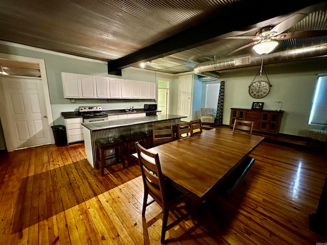 dining room featuring dark wood-style floors, beam ceiling, ceiling fan, and visible vents