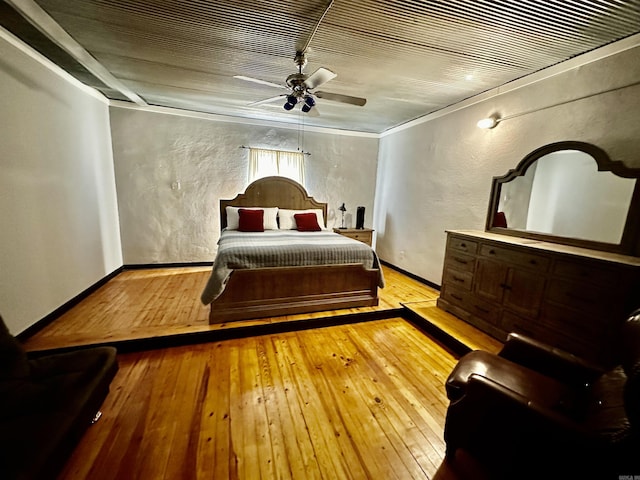 bedroom featuring ceiling fan, baseboards, hardwood / wood-style floors, and a textured wall