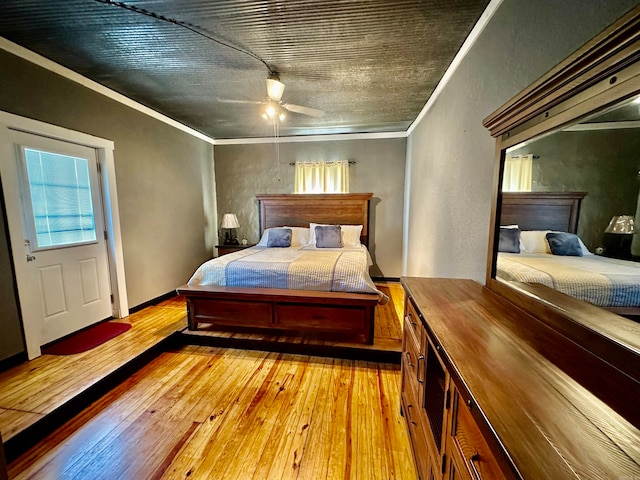 bedroom with light wood-style flooring, a ceiling fan, baseboards, and ornamental molding