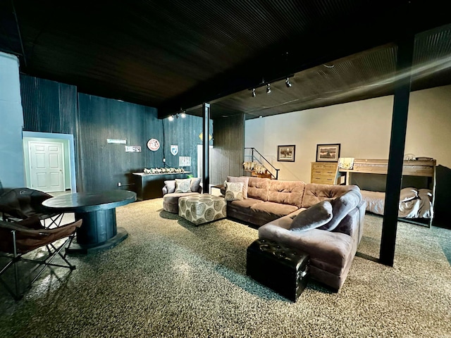 living area featuring beam ceiling, stairway, rail lighting, and carpet