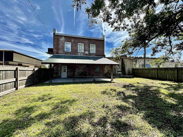 back of house featuring brick siding, a fenced backyard, a yard, and a patio